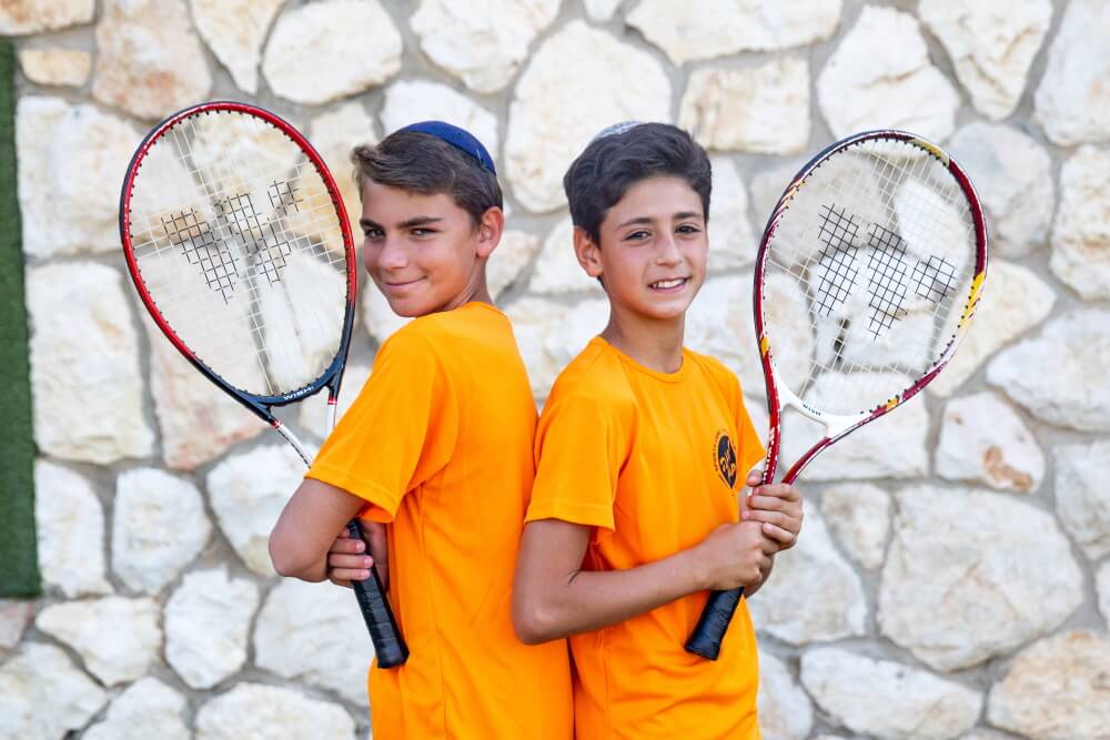 ילדים עומדים עם מחבטי טניס
